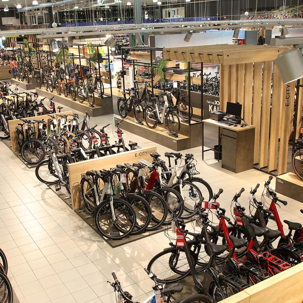 Fahrrad XXL Kalker Geschäft mit verschiedenen Fahrrädern und Holzregalen in heller Umgebung.